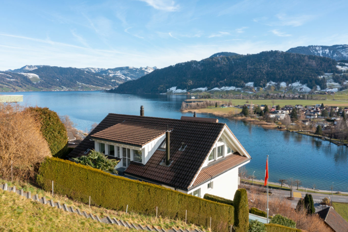 A house on a hill overlooking a lake.