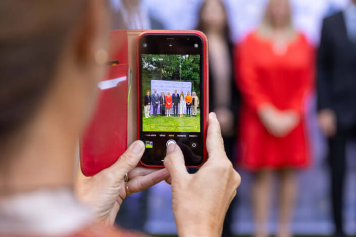 Eine Frau fotografiert eine Gruppe von Menschen.