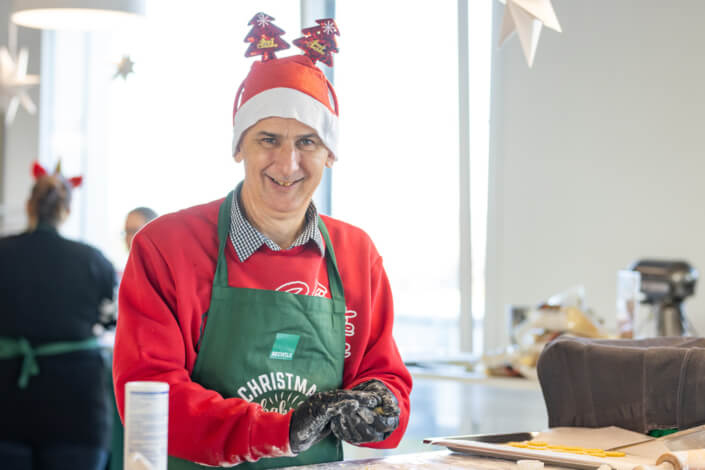 Ein Mann mit Weihnachtsmütze und Schürze.