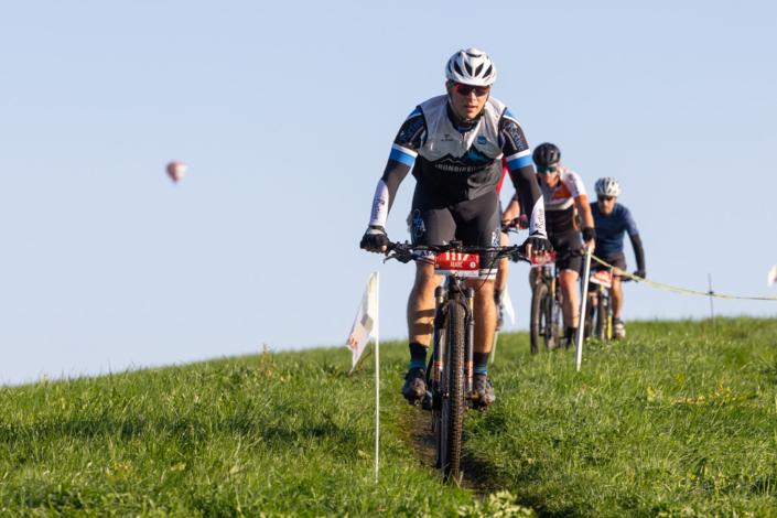 A group of mountain bikers ride down a hill.