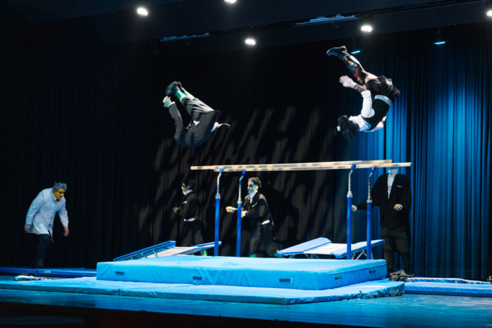 A group of people perform gymnastics on a stage.
