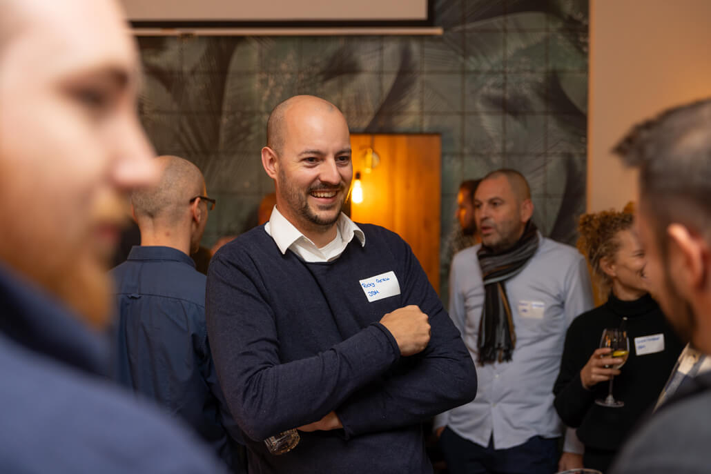 A man smiles at a party with other people.