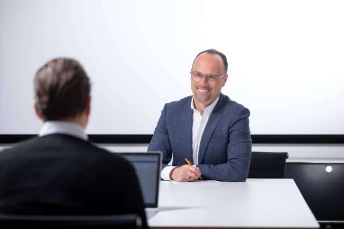 A man in a suit is sitting at a desk with a laptop.