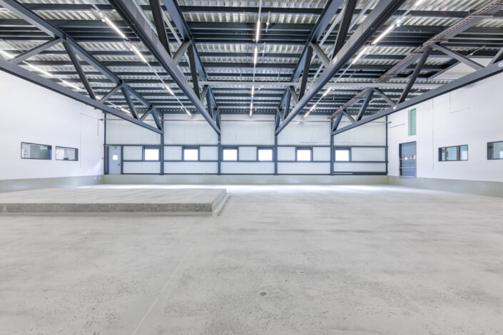 Eine leere Lagerhalle mit Betonböden und Fenstern.