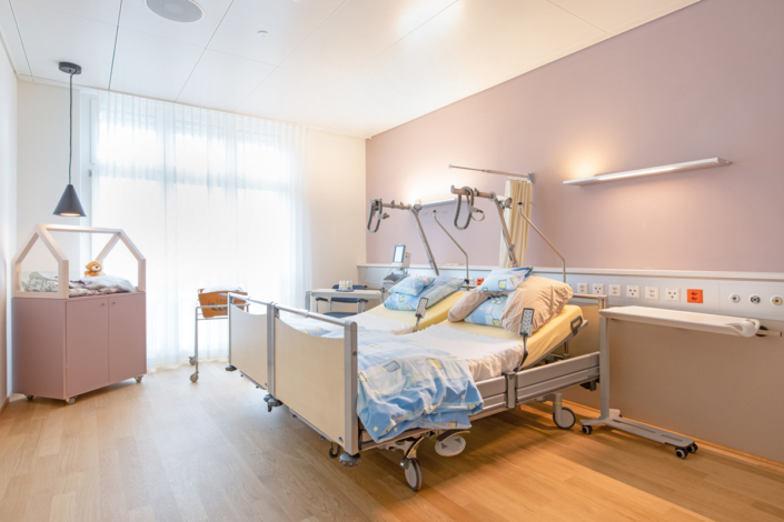 A hospital room with a bed and a bedside table.