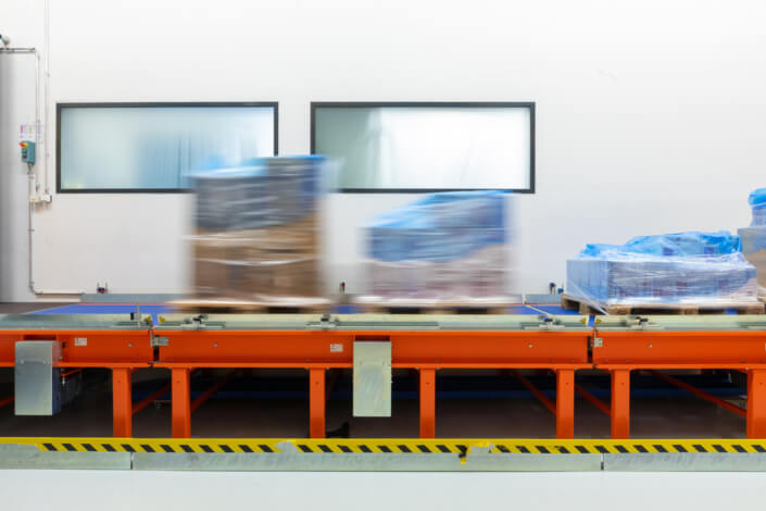 A conveyor belt in a warehouse with blue sacks on it.