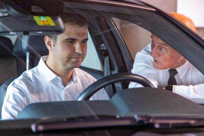 Two men in a car talking to each other.