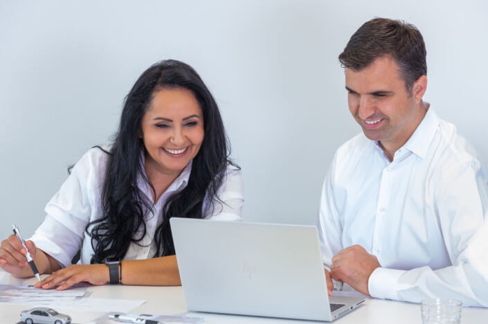 Ein Mann und eine Frau sitzen an einem Tisch und schauen auf einen Laptop.