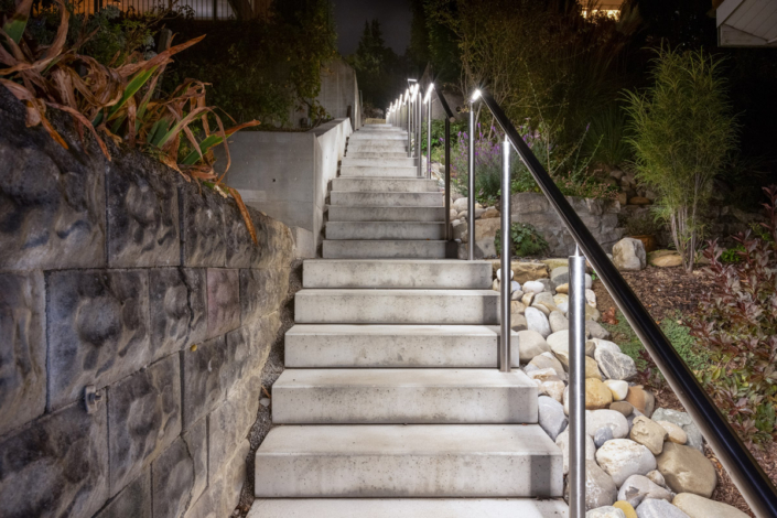 A concrete staircase that leads to a stone wall at night.