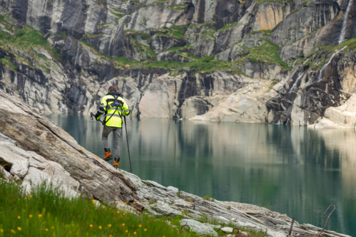 A man stands on a cliff near a body of water.