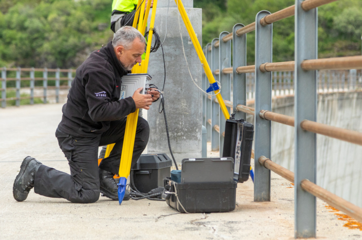 A man works with a device on a bridge.