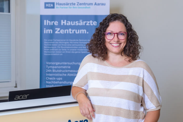 A woman stands in front of a sign.