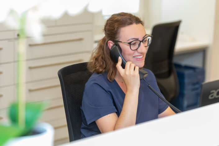 Eine Frau sitzt am Schreibtisch und telefoniert.