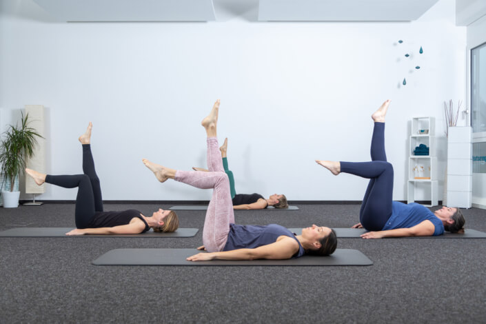 Eine Gruppe von Frauen macht Yoga in einem Raum.