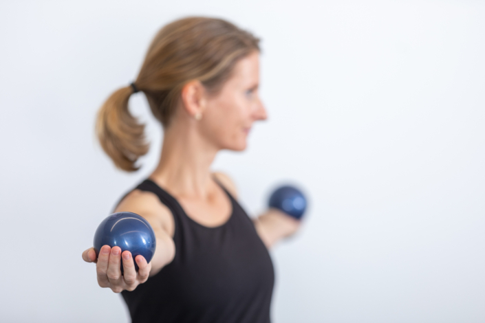 A woman holds a pair of dumbbells in her hands.