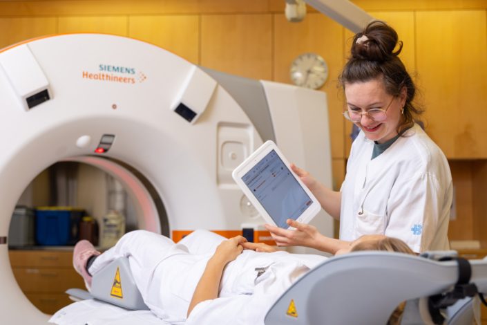 A woman in a lab coat looks at an MRI machine.
