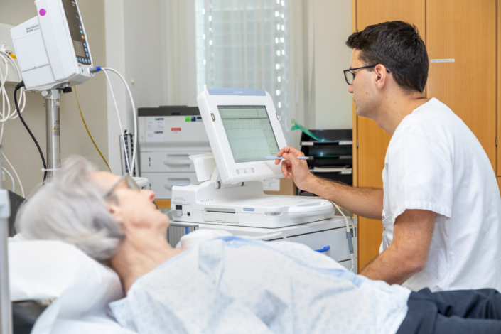 A nurse looks at a patient in a hospital bed.