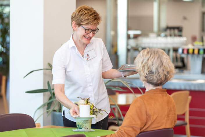 Eine Frau bedient eine Frau in einer Cafeteria.