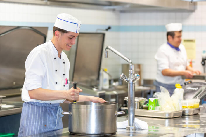 A group of men prepare food in a kitchen.