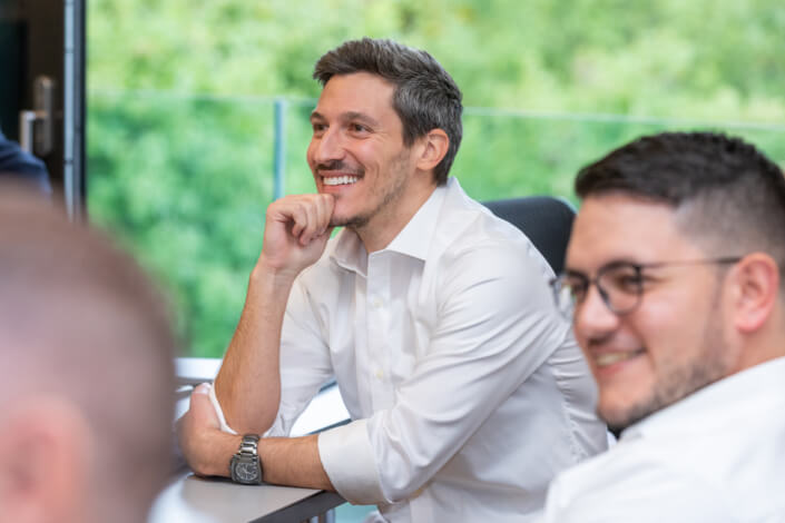 A group of men sit at a table and smile.