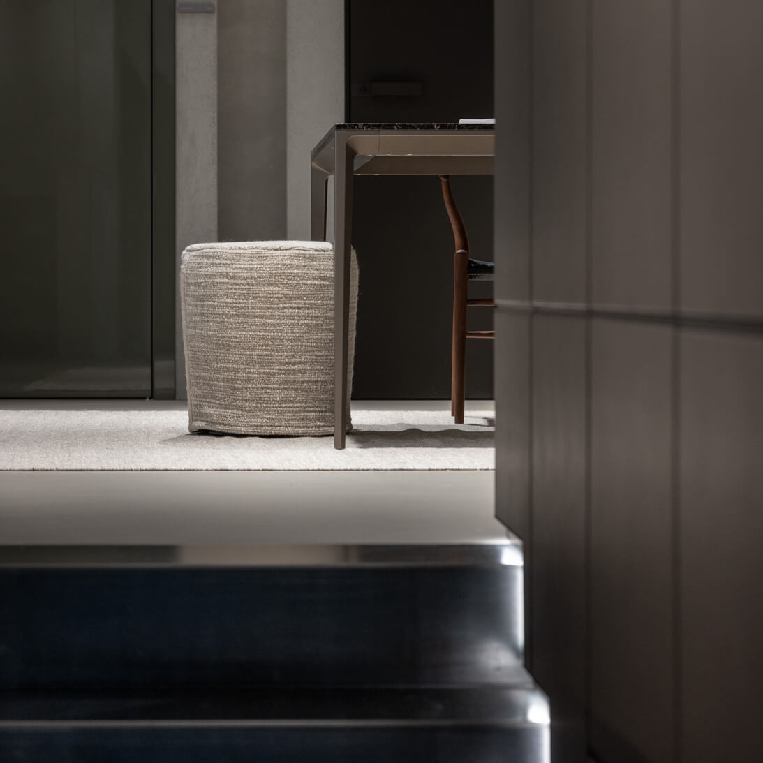 A dark room with a staircase and table, beautifully captured by an architectural photographer.