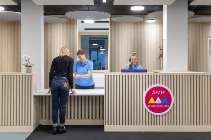 Two women are standing at the reception desk.